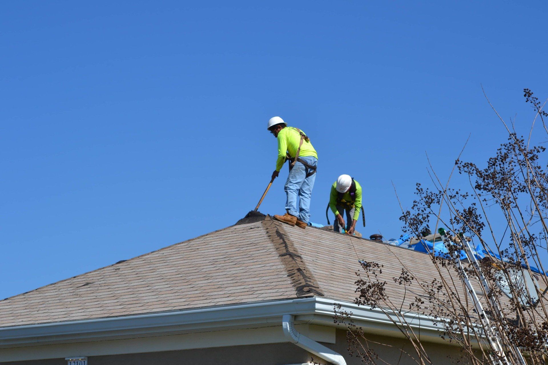 Two men are working on the roof of a house.
