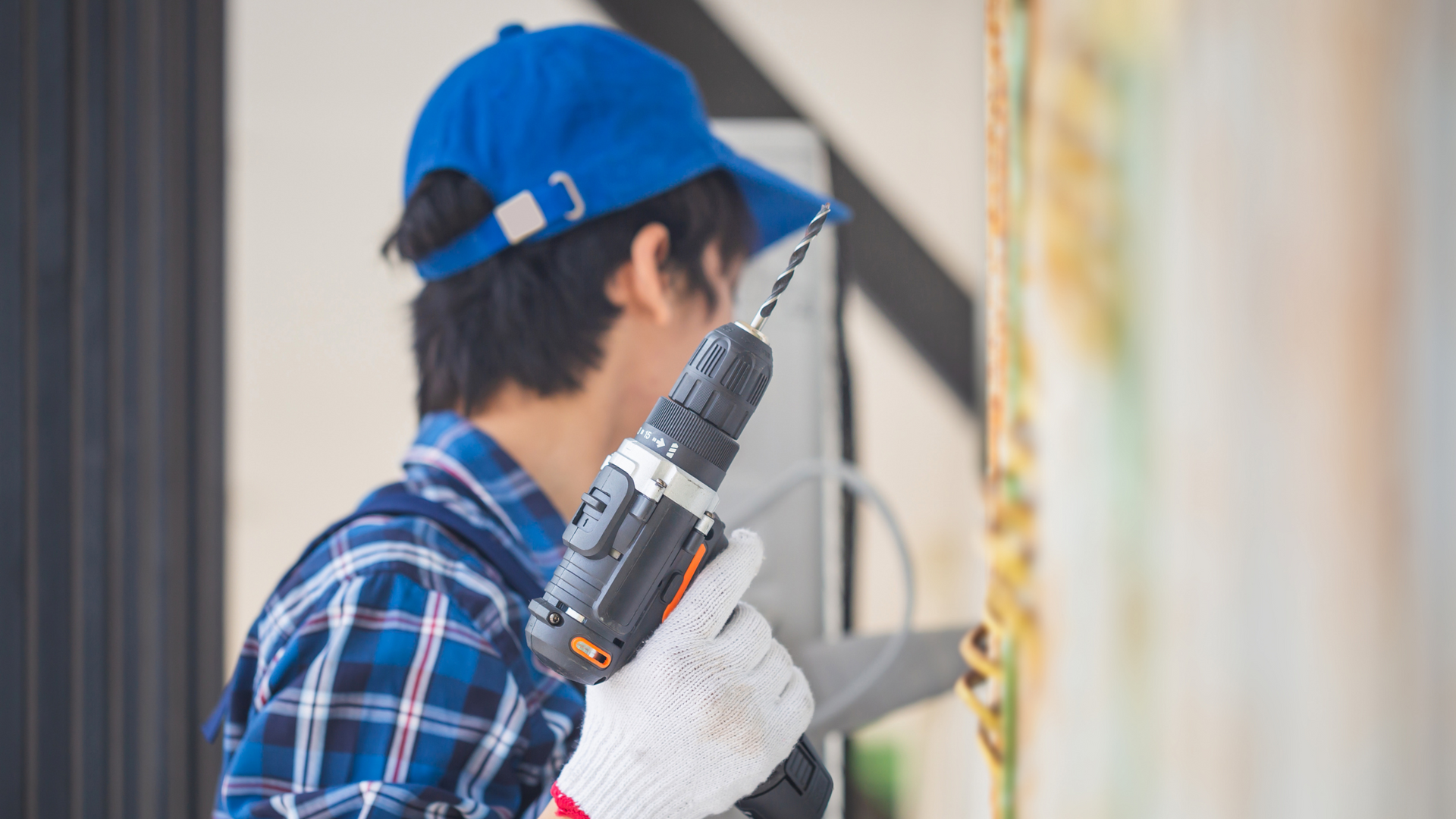 A man in a blue hat is holding a drill.