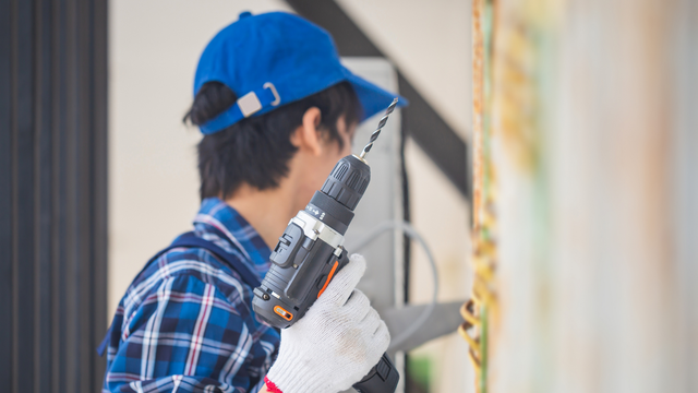 A man in a blue hat is holding a drill.