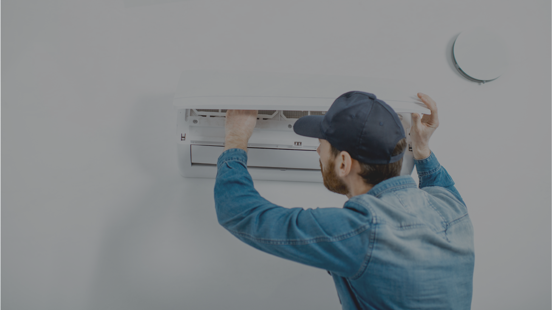 A man is installing an air conditioner on a wall.