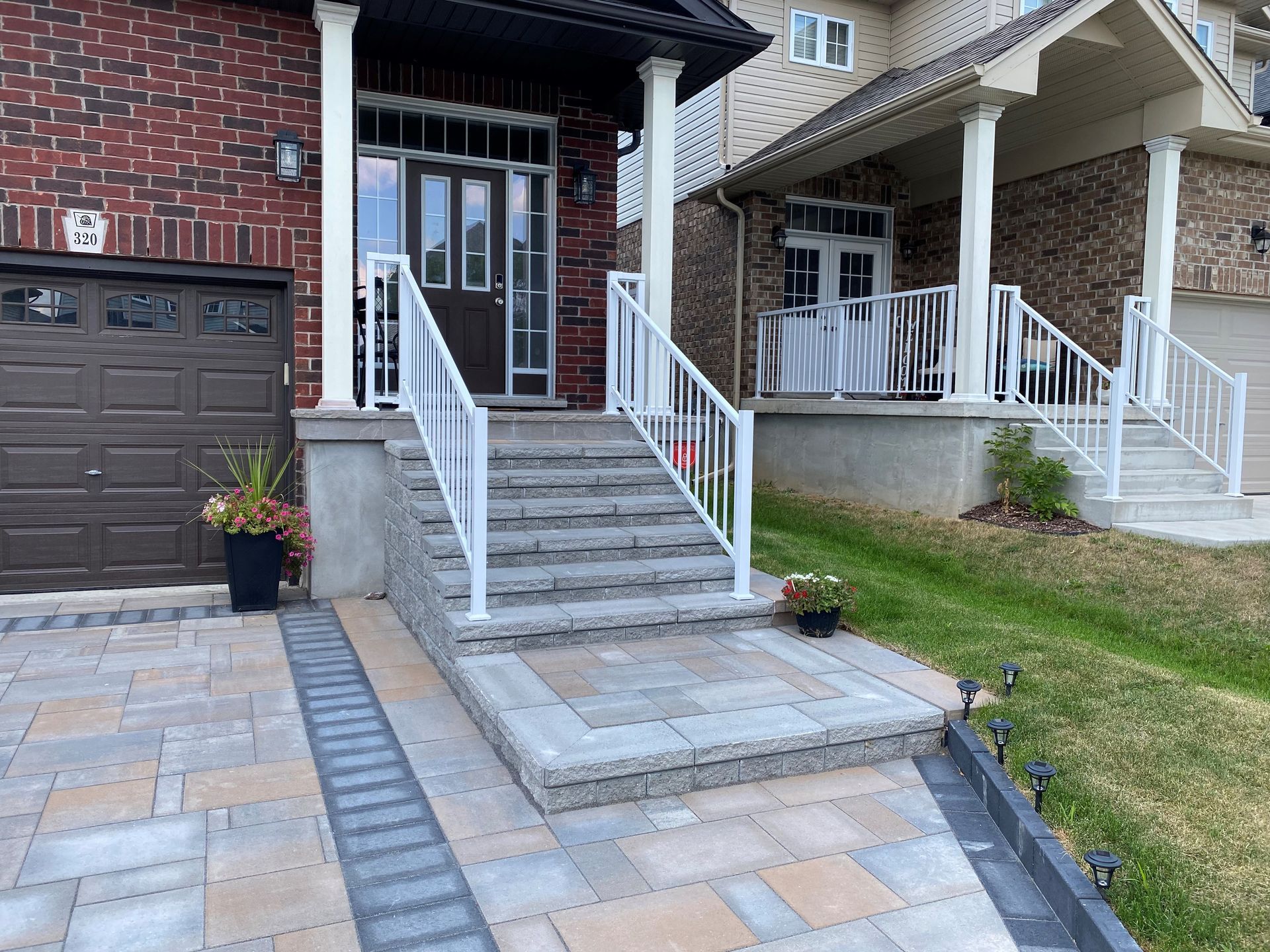 Brick house with steps, white railing, and paved entrance.