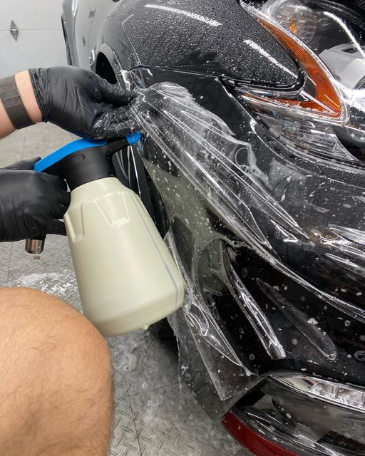 Detailing spray on a black car bumper during washing