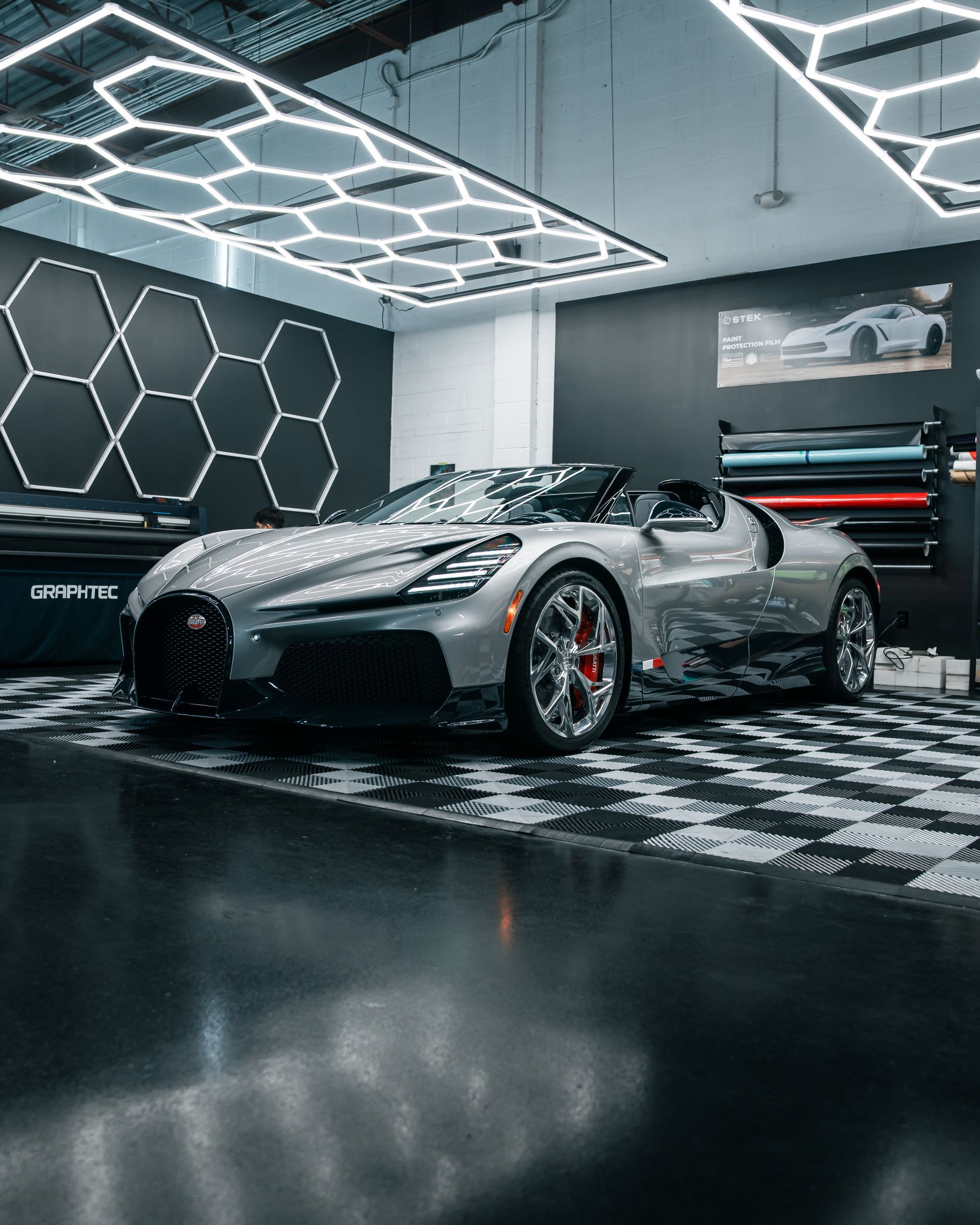 Silver sports car in a neon-lit showroom with hexagonal wall lighting