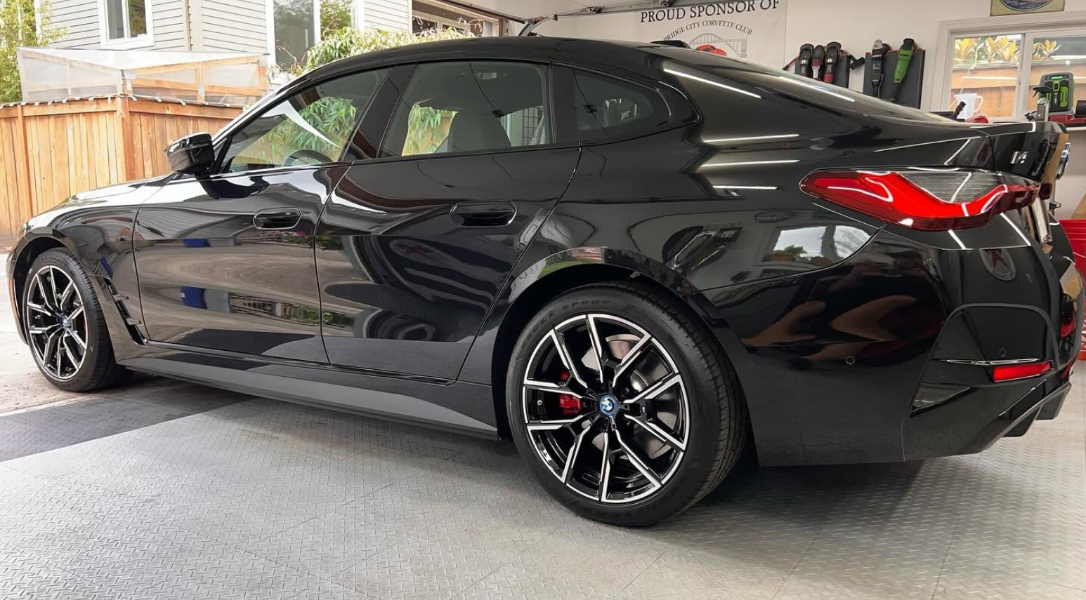 Black sports coupe parked in a garage, side view with glossy finish and red brake calipers
