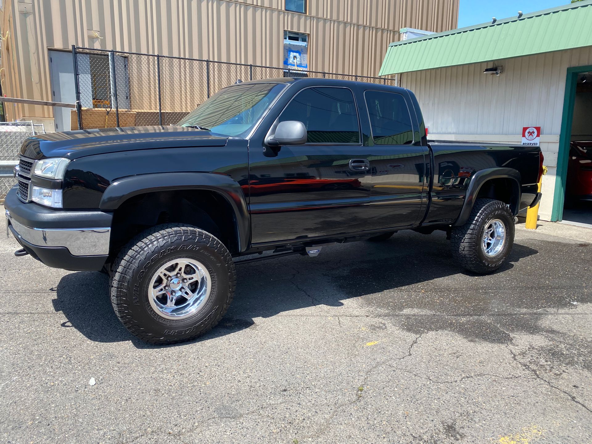 Black lifted pickup truck parked outside a garage on a sunny day