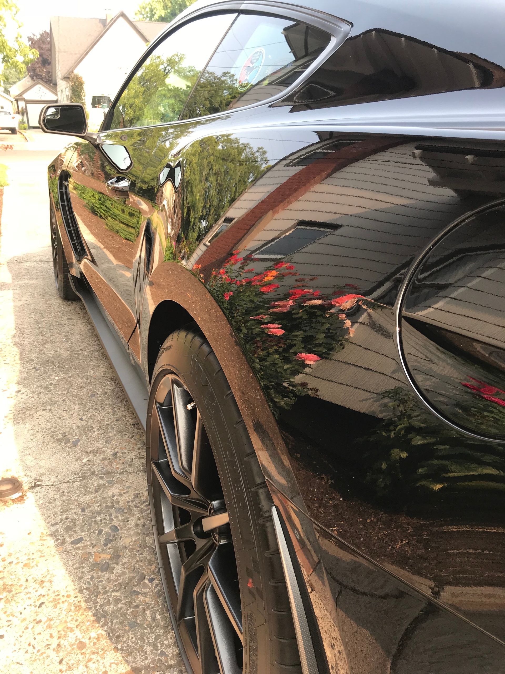 Black sports car parked outdoors, side view with shiny reflections on the body