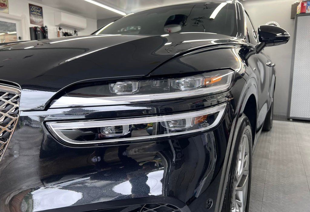 Black SUV with a shiny finish, parked indoors. Front view showcasing the headlights and grille.