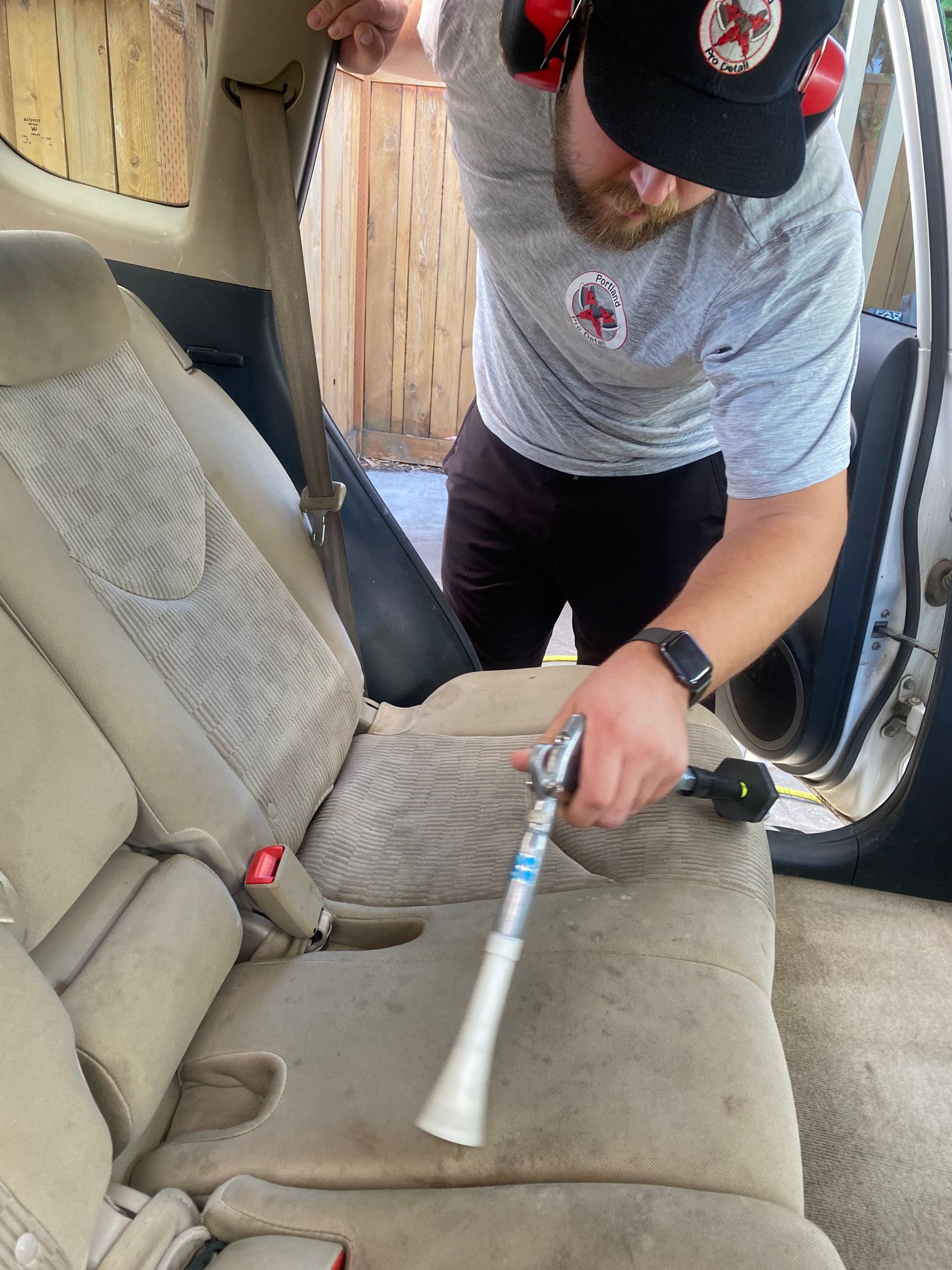 Gloved hand painting white geometric lines on a dark car hood with a sponge applicator
