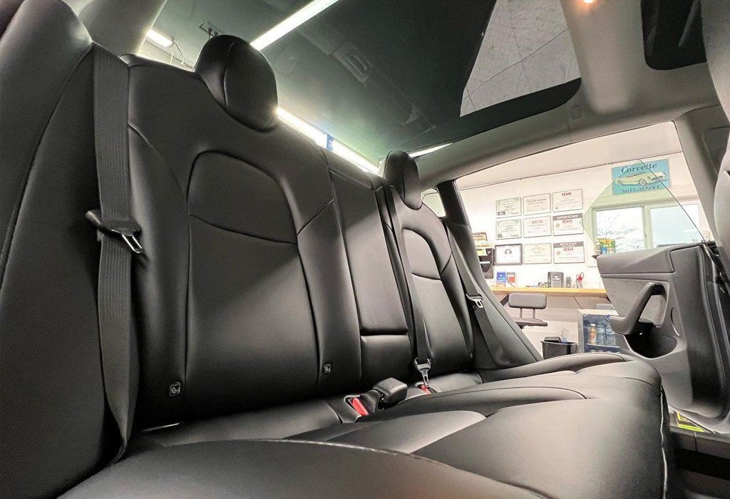 Black leather car back seats. Window shows an office with a desk.