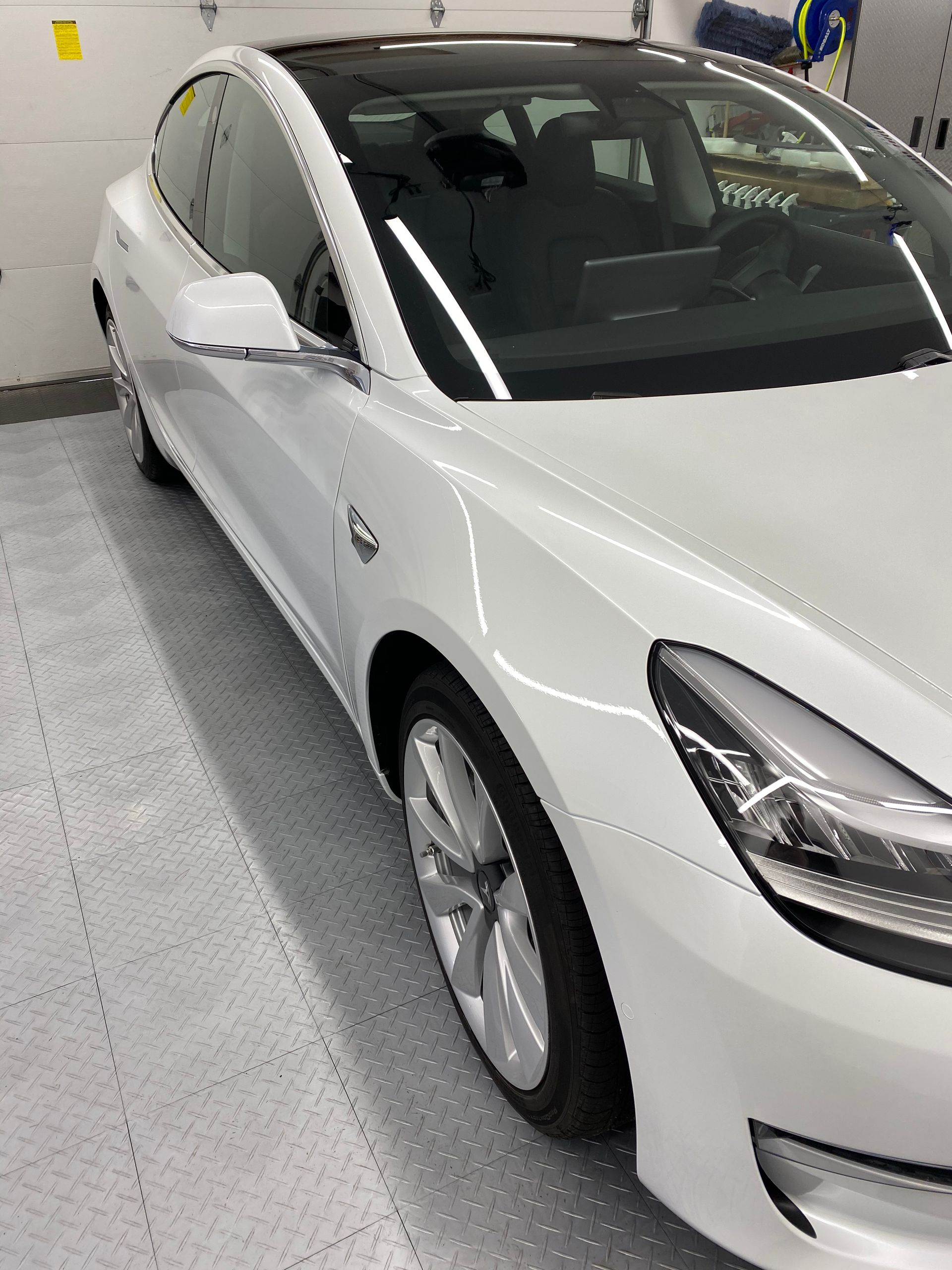 White sedan parked in an indoor garage, front-left view