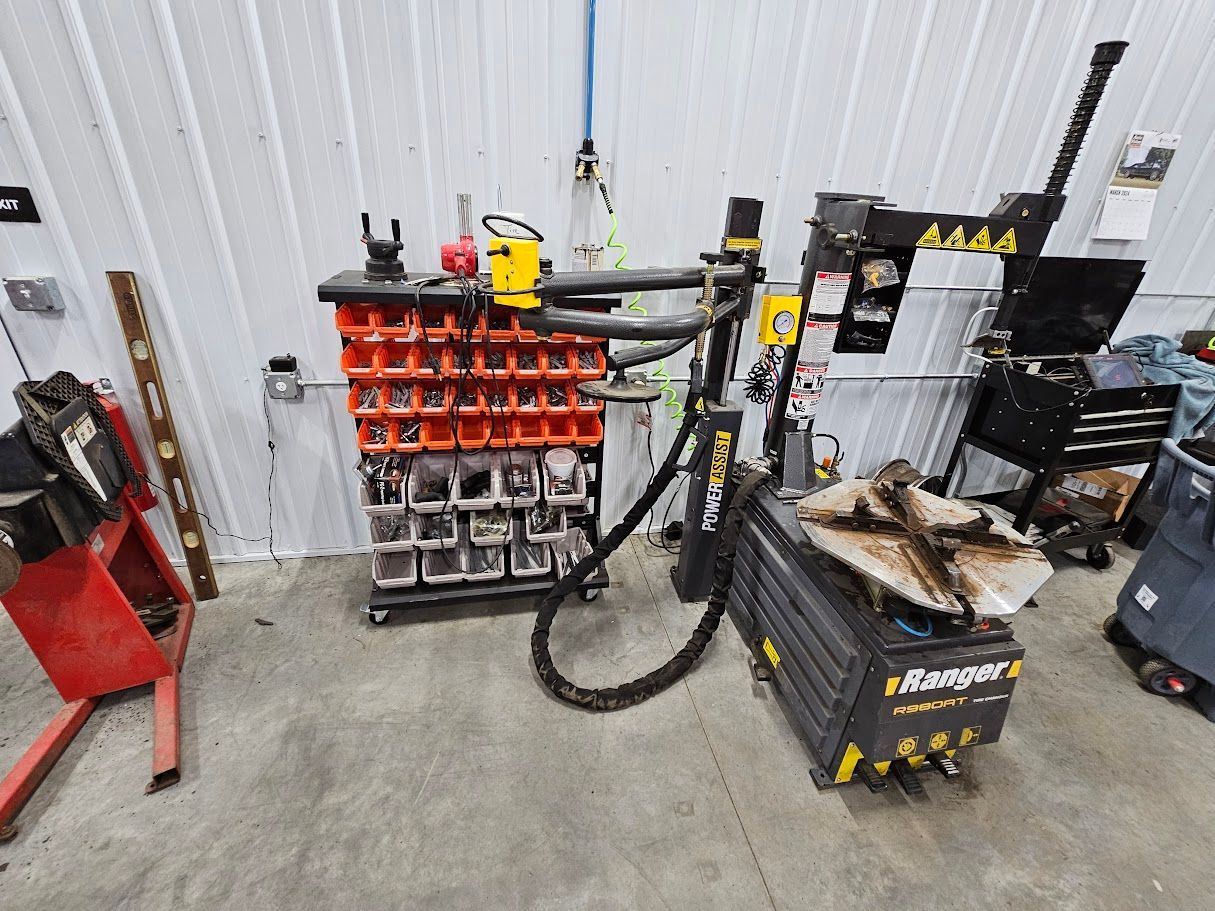 a tire changer is sitting in a garage next to a tire balancing machine .