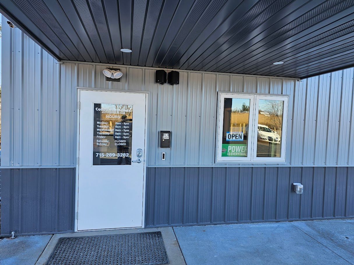 a gray building with a white door and two windows