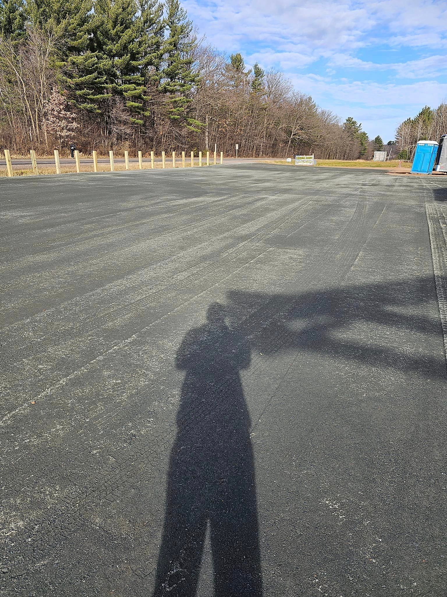 a shadow of a person is cast on the ground in a parking lot .