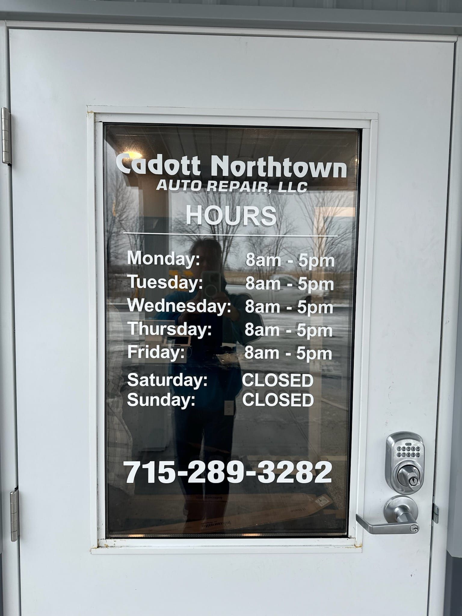 a door with a sign on it that says `` cadott northtown auto repair llc hours '' .