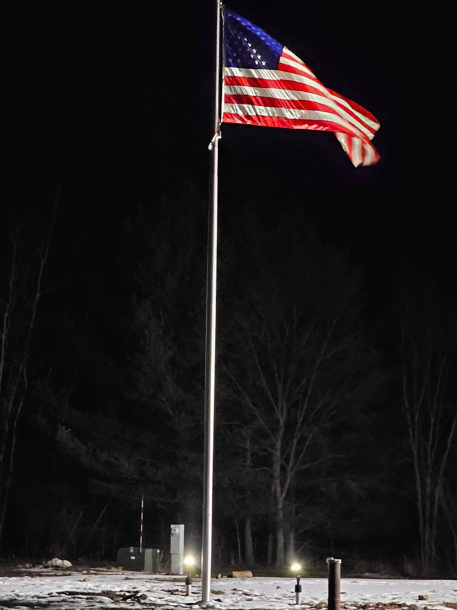 an american flag is flying in the wind at night