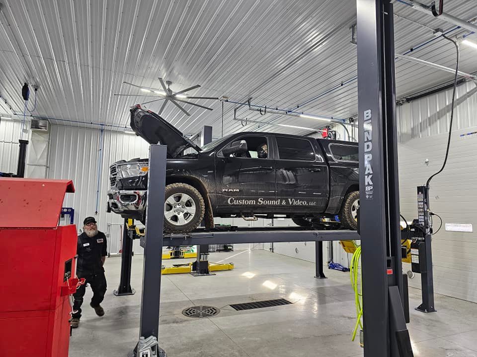 a black truck is sitting on a lift in a garage .