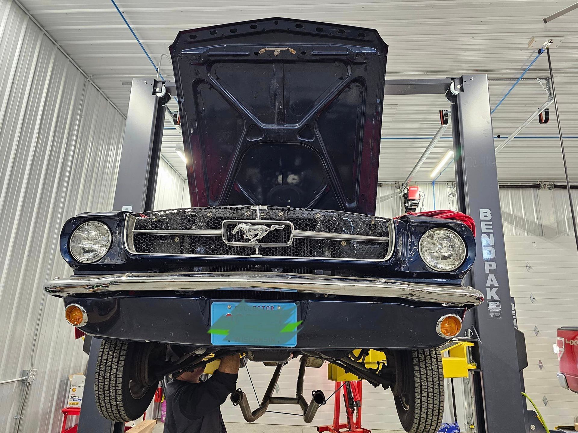 a man is working on a mustang on a lift in a garage .