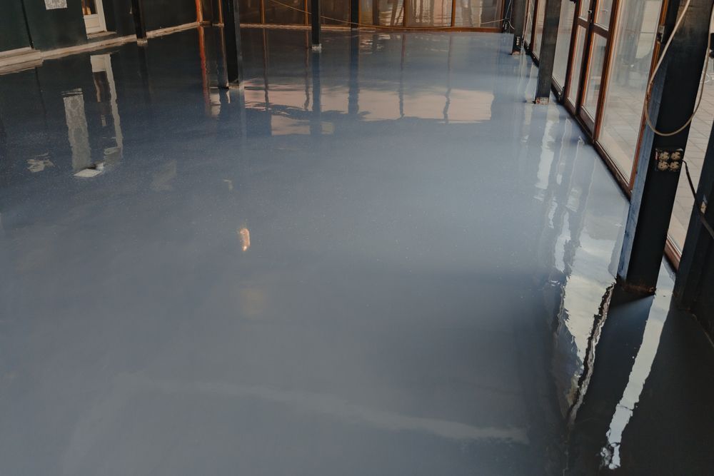Glossy gray epoxy floor in a construction site with wooden framing reflections