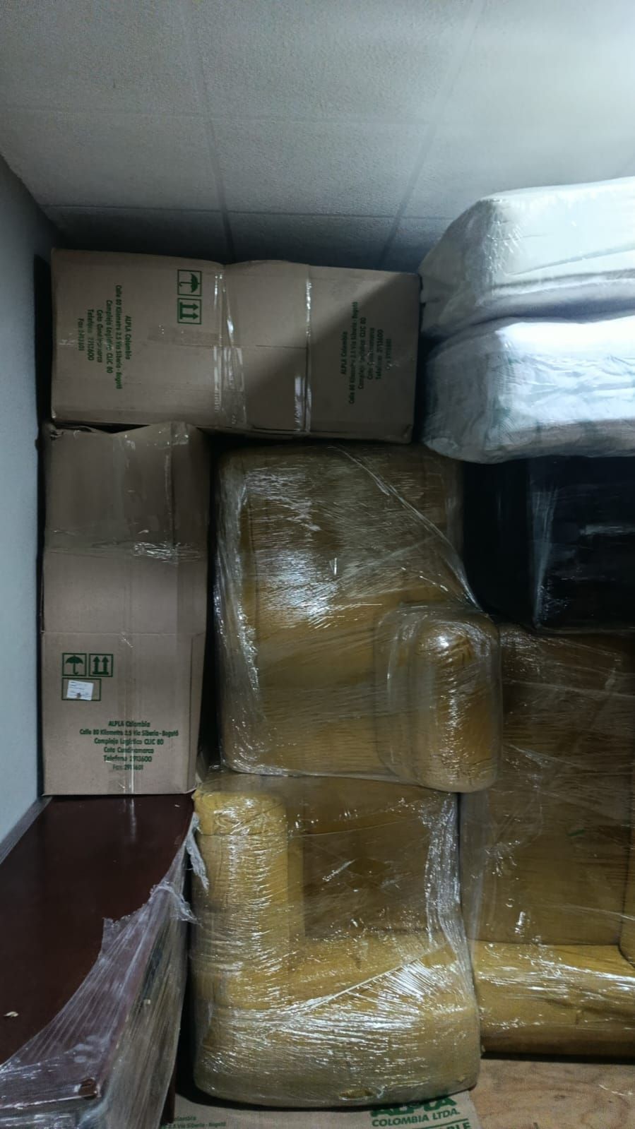 Cajas de cartón apiladas y paquetes envueltos amontonados en un trastero.
