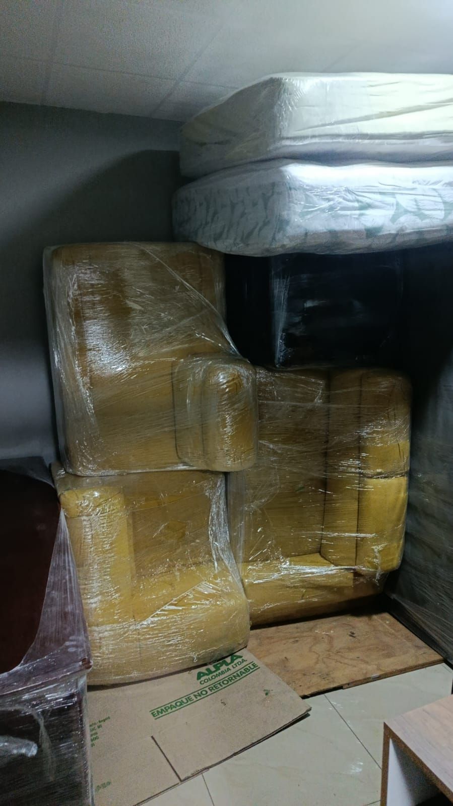 Cajas de cartón apiladas y envueltas en cinta amarilla sostienen un objeto negro