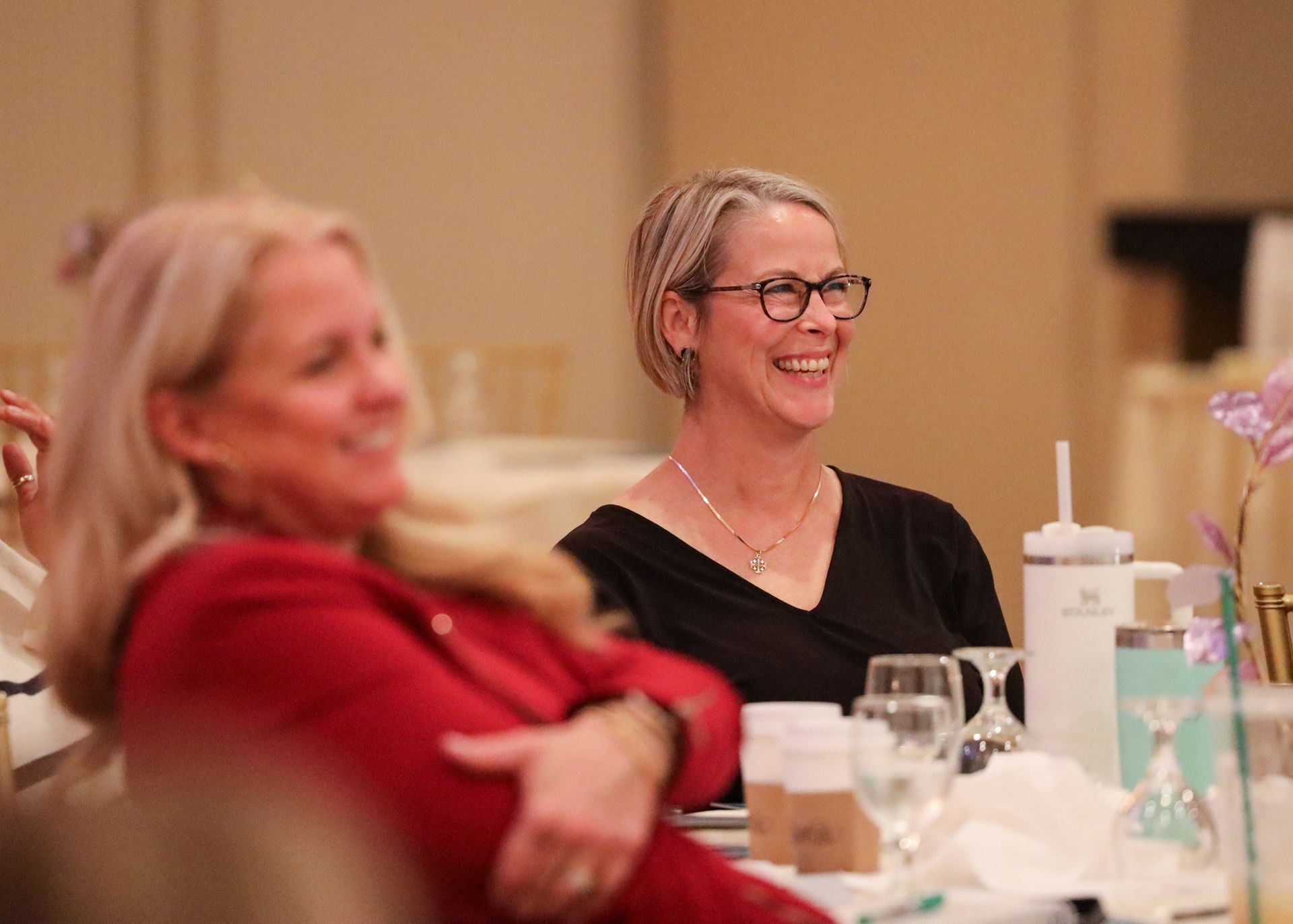 Two smiling people seated at a table in a softly lit indoor event setting