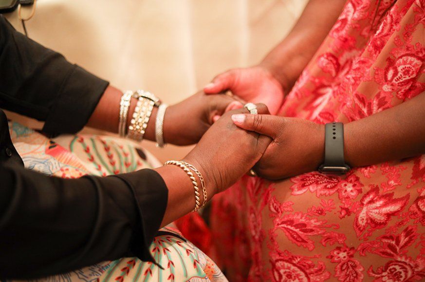 A zoomed in image of two  women holding hands in understanding