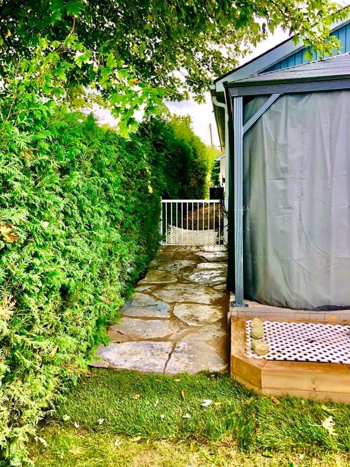 There is a walkway leading to a gazebo in the backyard.