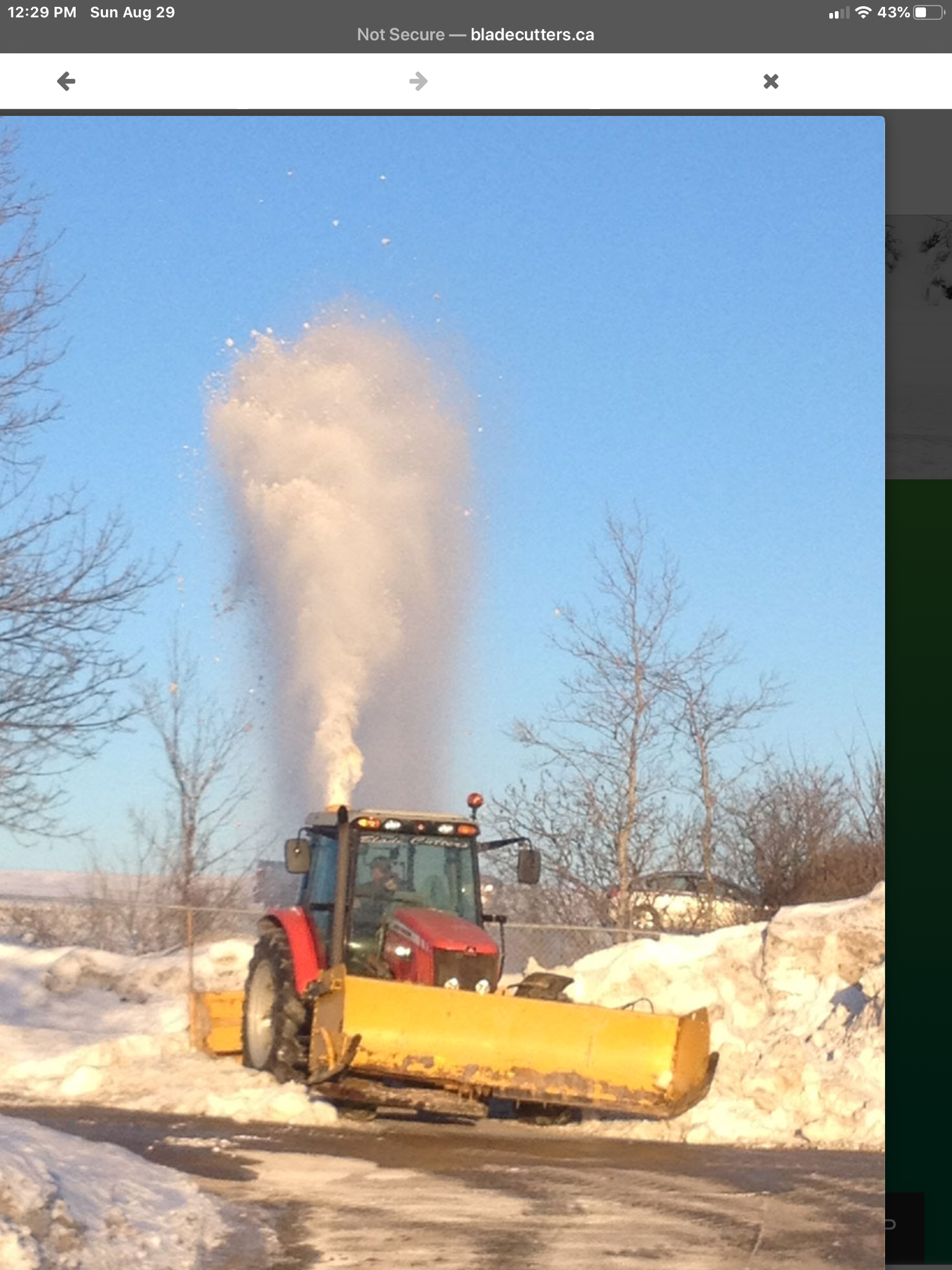 A snow plow is blowing smoke into the air