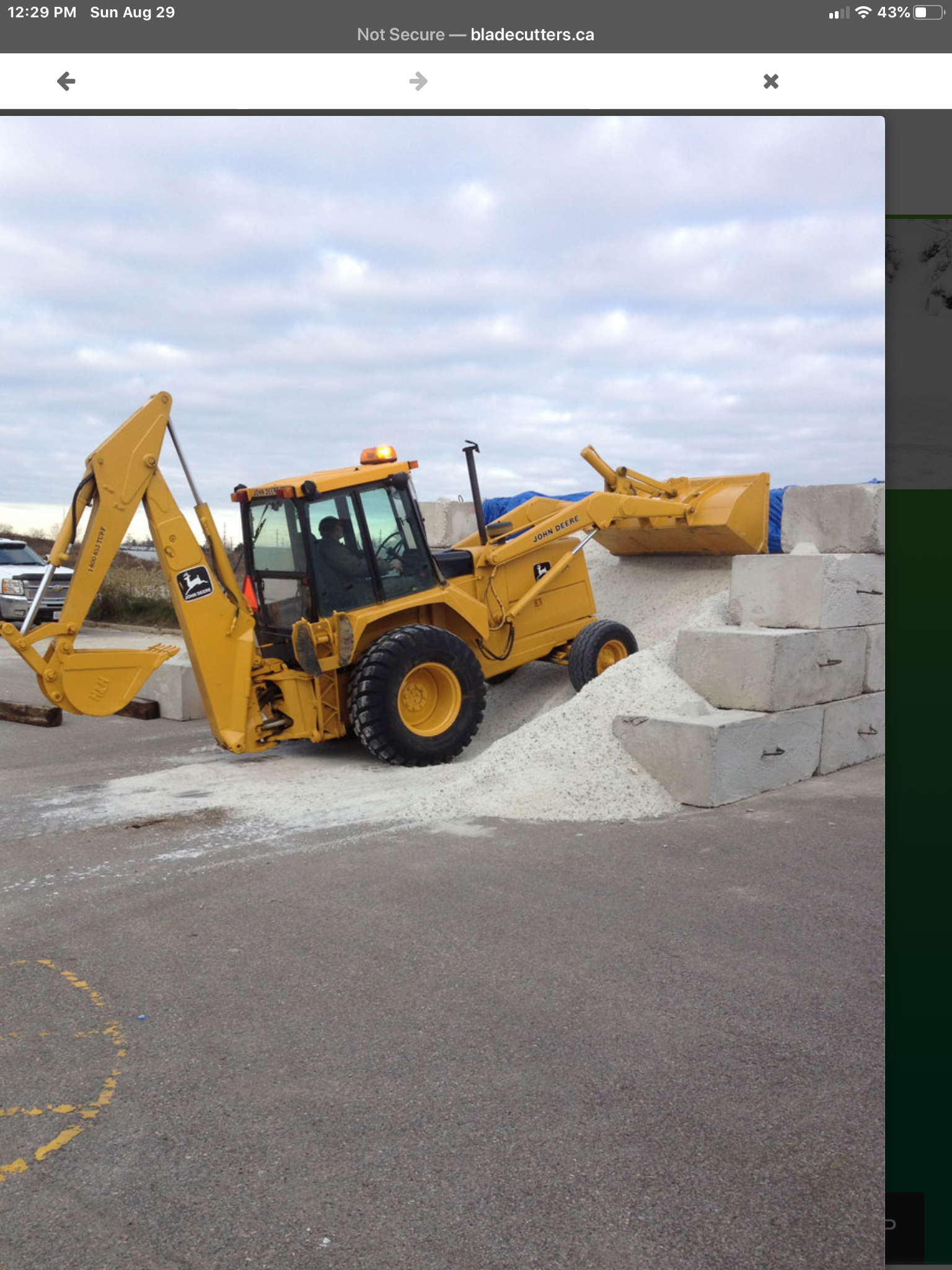 A yellow backhoe is sitting on top of a pile of salt