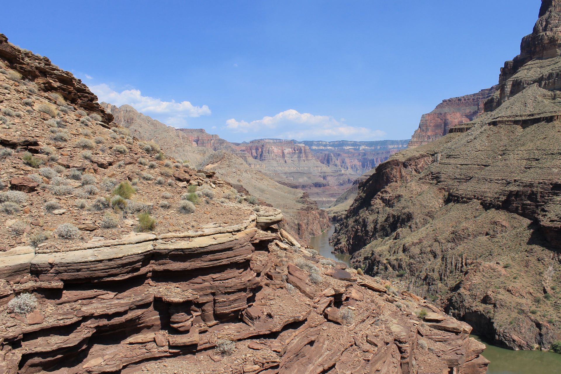 View of the Grand Canyon's layered rock formations under a bright blue sky.