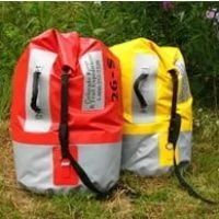 Two waterproof, roll-top duffel bags: red and yellow with reflective stripes, sitting on grass.