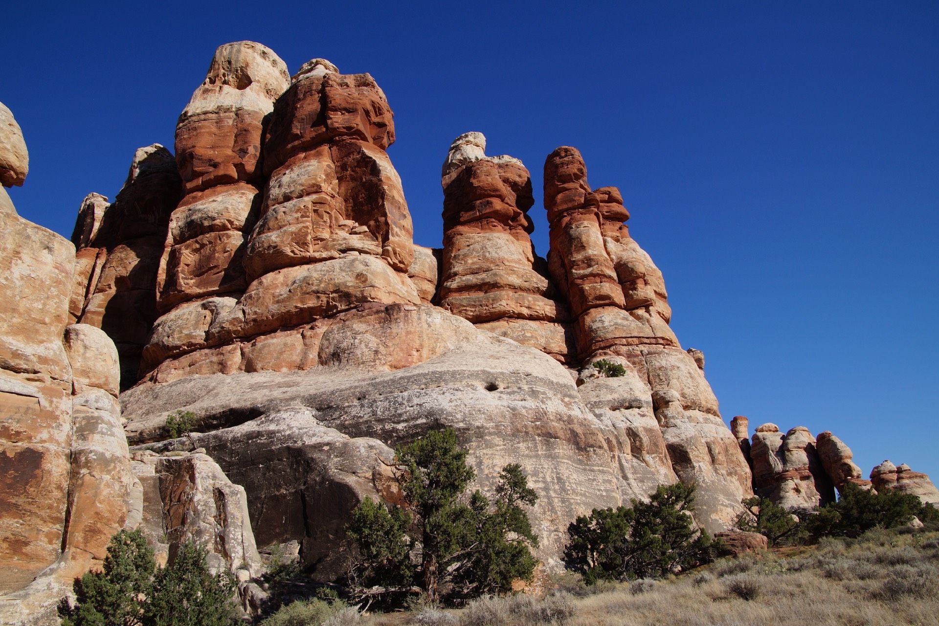 Red and white sandstone rock formations against a bright blue sky.