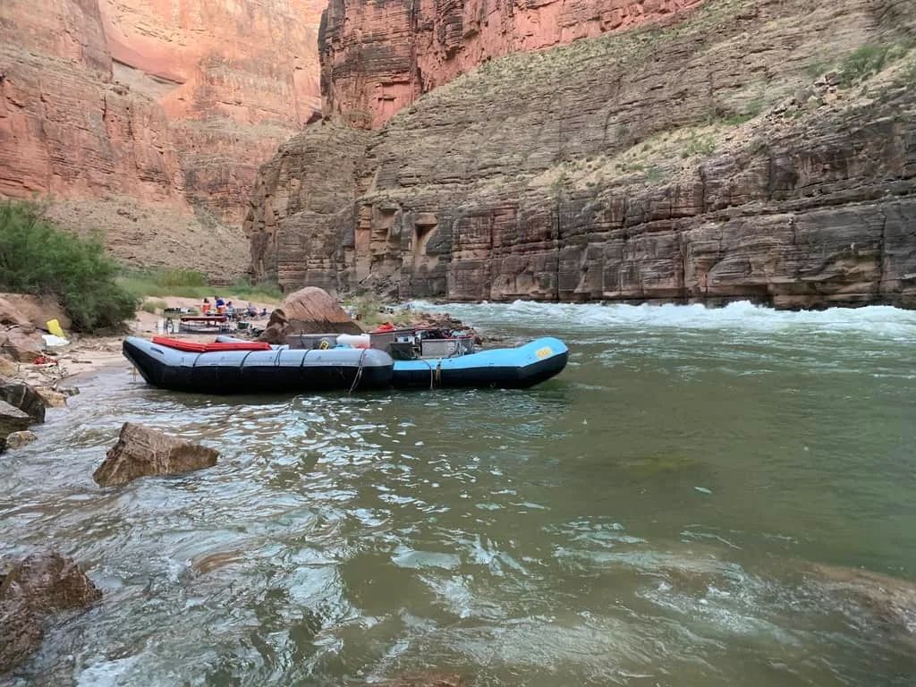 Raft on a river near rocky cliffs. The water is choppy.