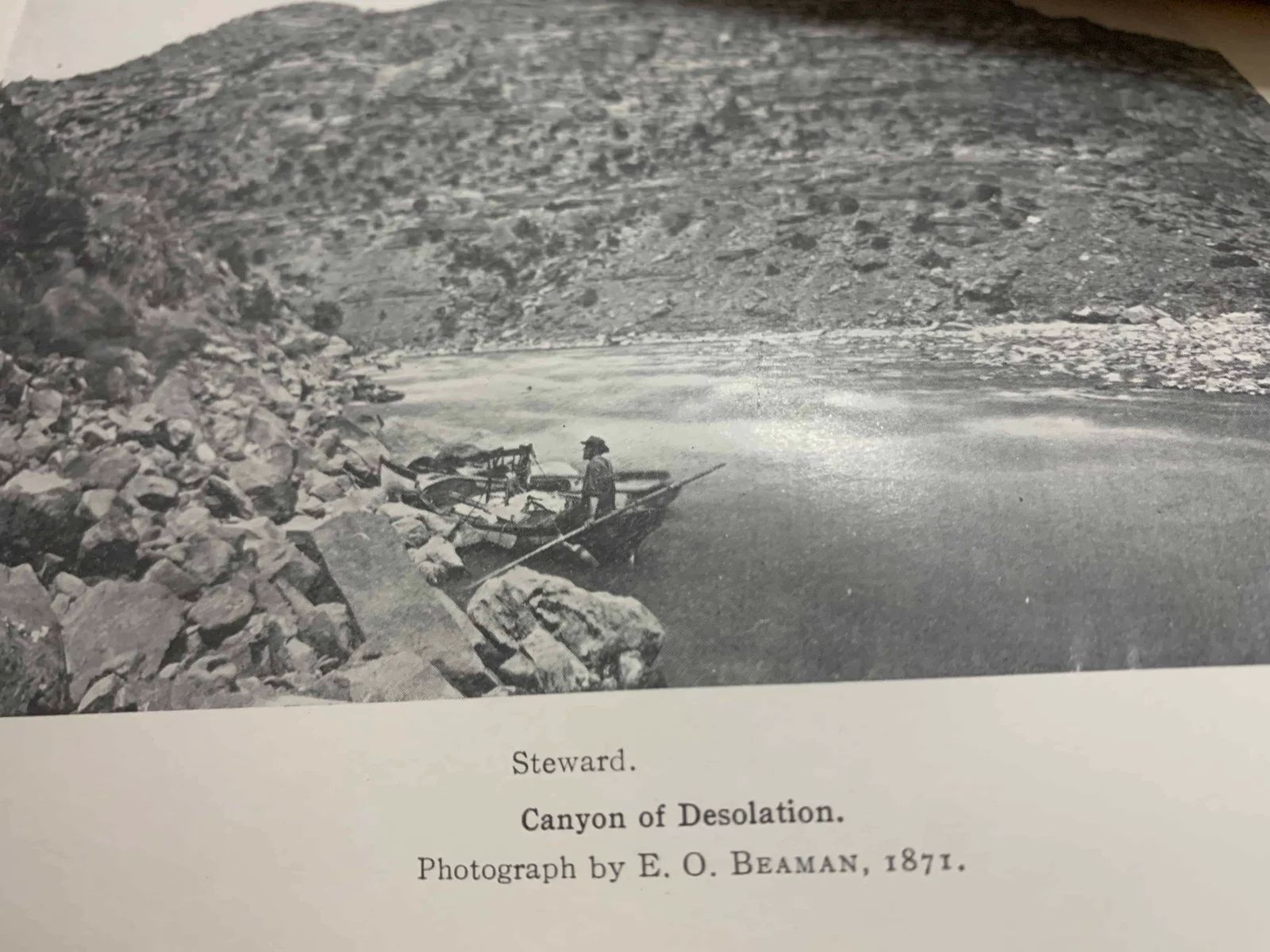 Man in boat on river in Canyon of Desolation, 1891. Rocky shoreline and canyon walls.