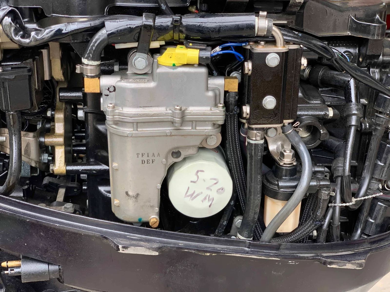 Boat engine with fuel filter. Black metal frame, grey fuel filter housing, hoses, and wiring.