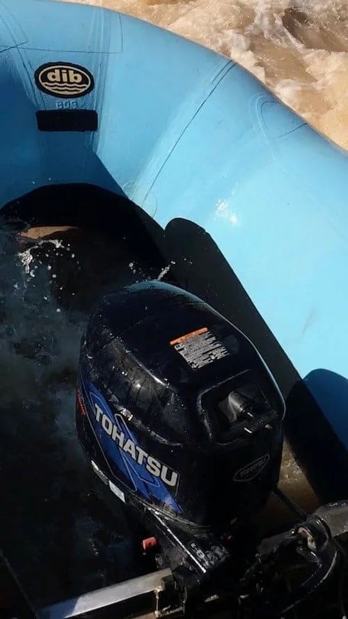 Blue inflatable boat with a Tohatsu outboard motor on choppy water.