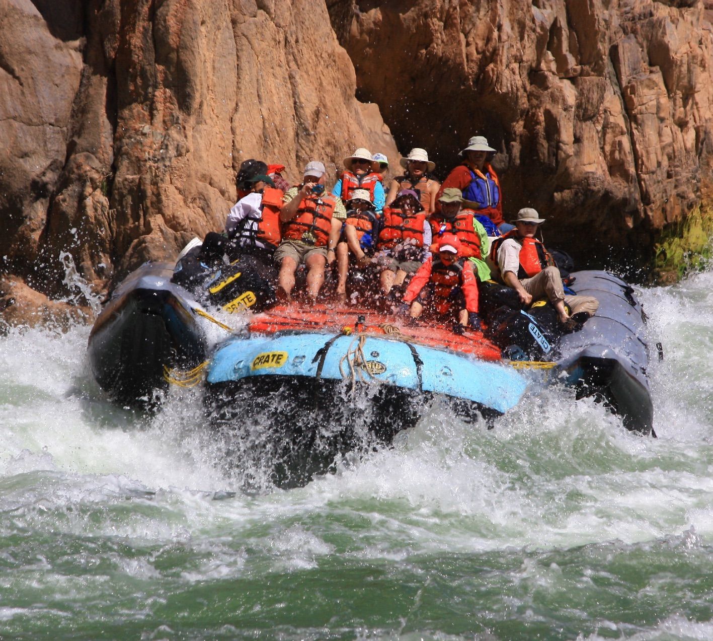 Group of people on a white water rafting through a narrow canyon