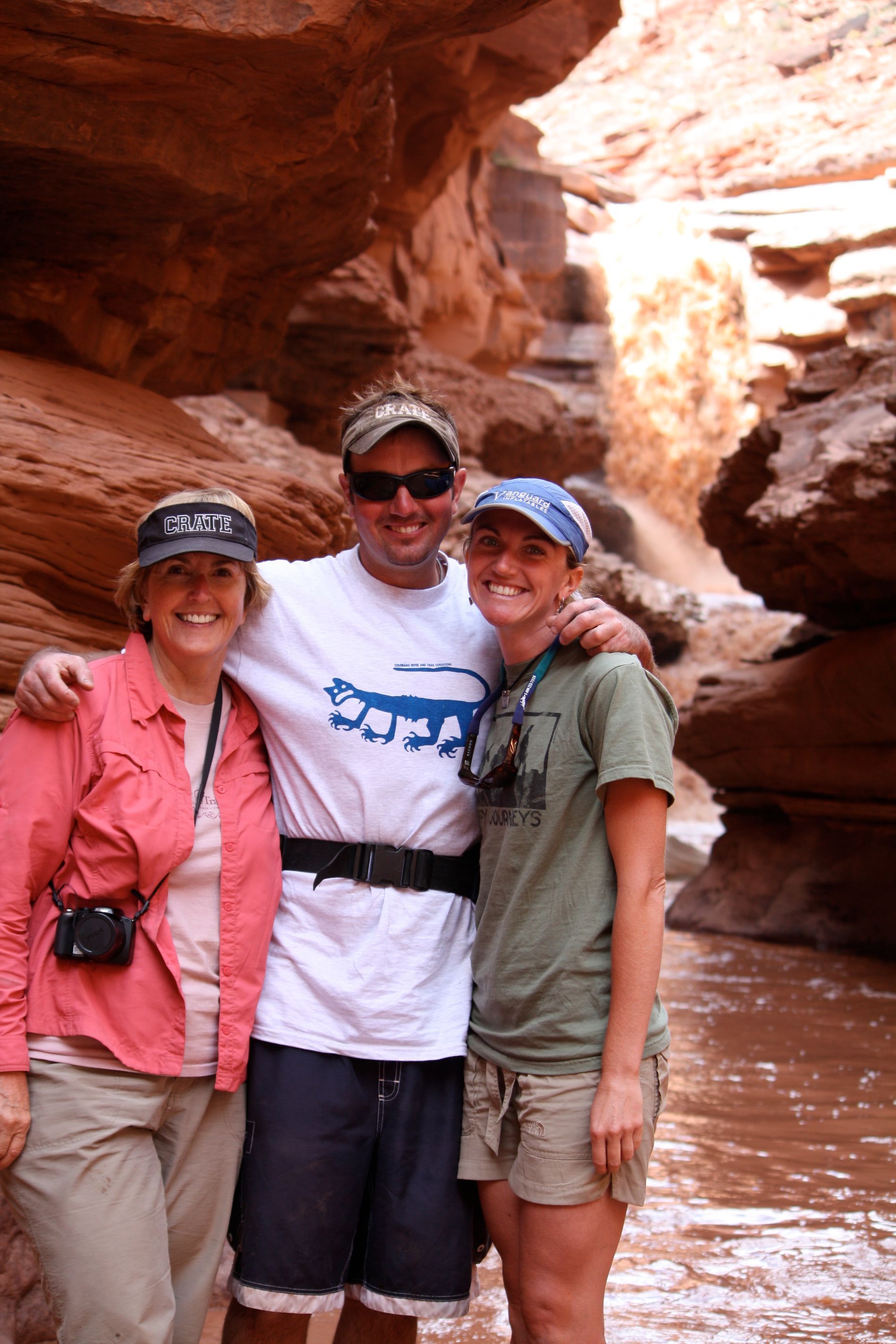 Three people pose for a photo in a red rock canyon.
