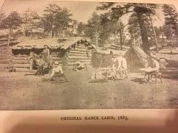 Black and white photograph of original Hance Cabin, 1885. People near log cabins and tents.