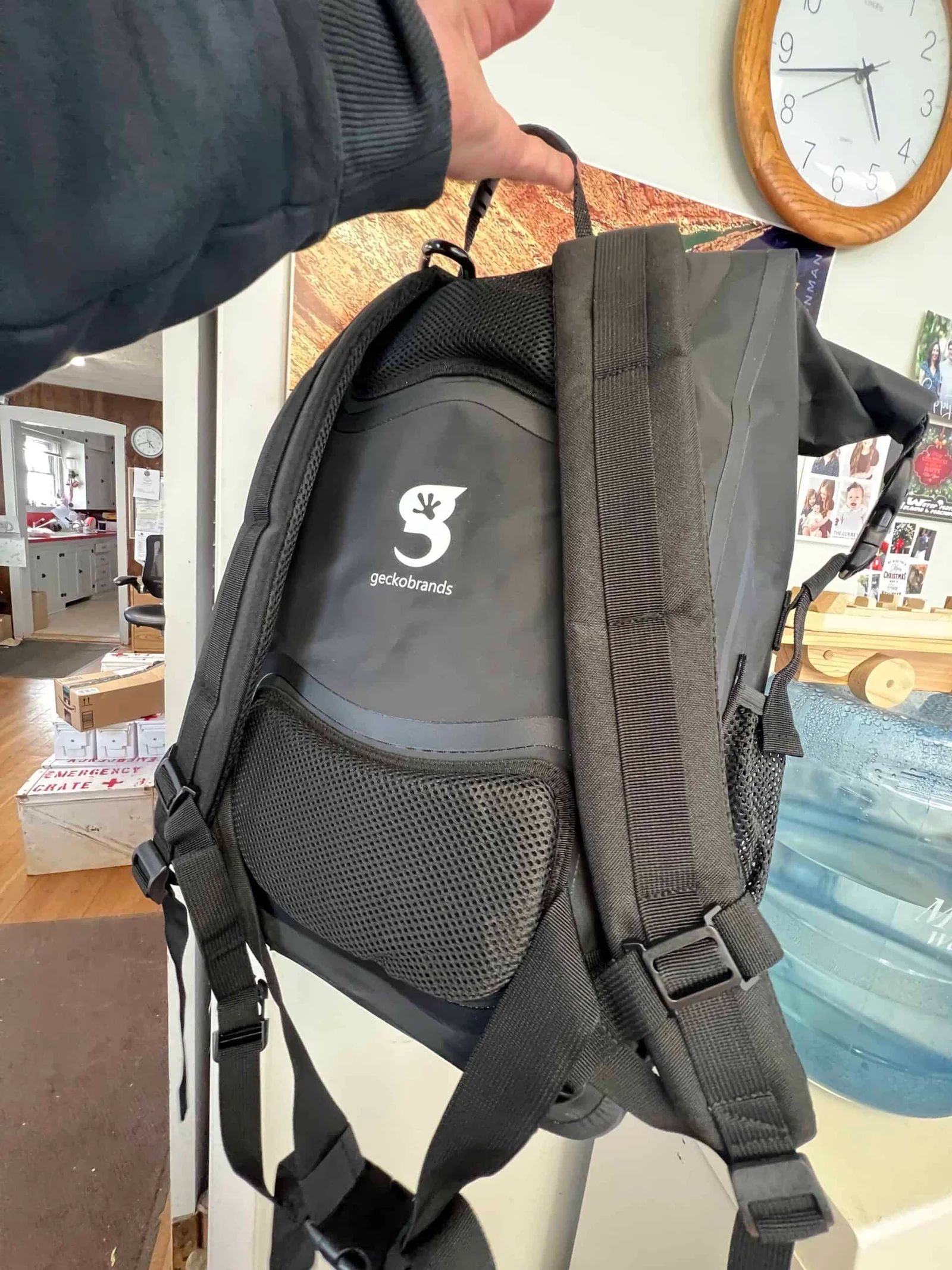 Black backpack with padded back and straps, held by a person's hand.