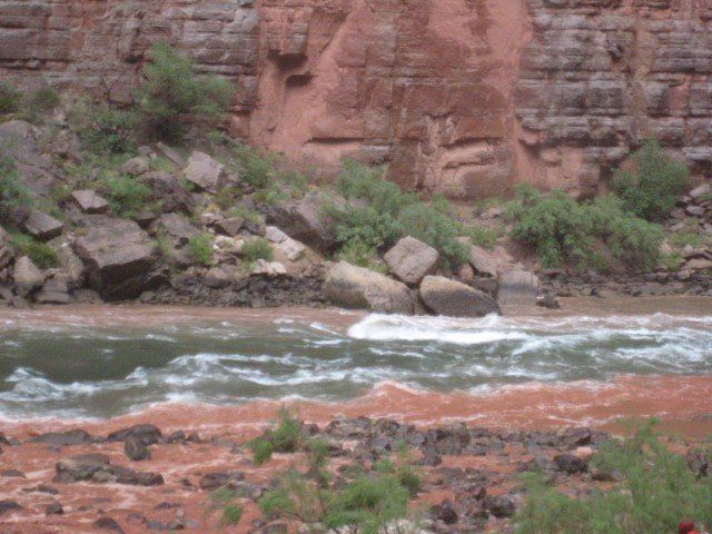 Whitewater river flowing between red rock canyon walls.
