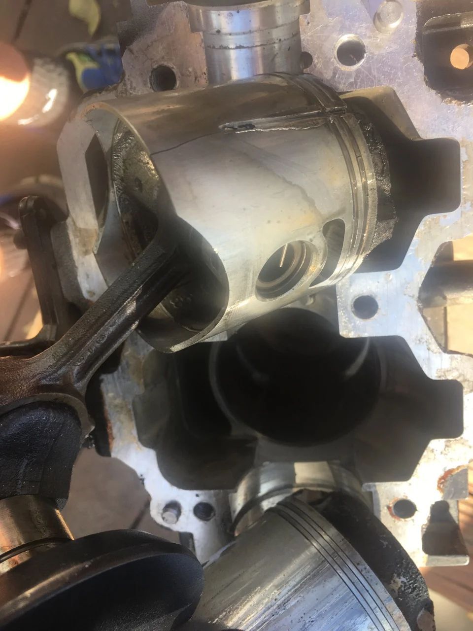 Engine block with piston, connecting rod, and crankshaft visible. Components are gray metal, partially disassembled.
