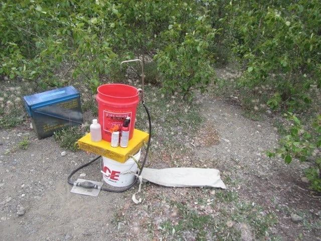 A scientific setup in nature: a bucket-based filtration system next to vegetation.