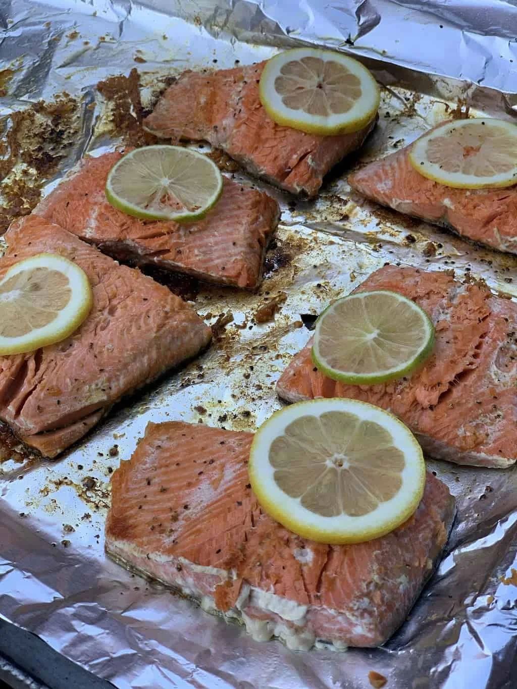 Baked salmon fillets with lemon slices on foil.