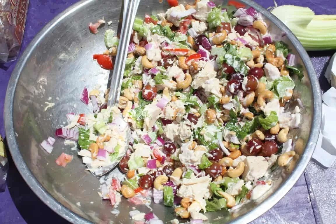 Large silver bowl filled with chicken salad, vegetables, and cashews.