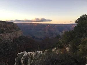 Grand Canyon view at dusk with canyon walls and cloudy sky.