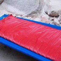 Red water bladder inside a blue tray, sitting near rocks.