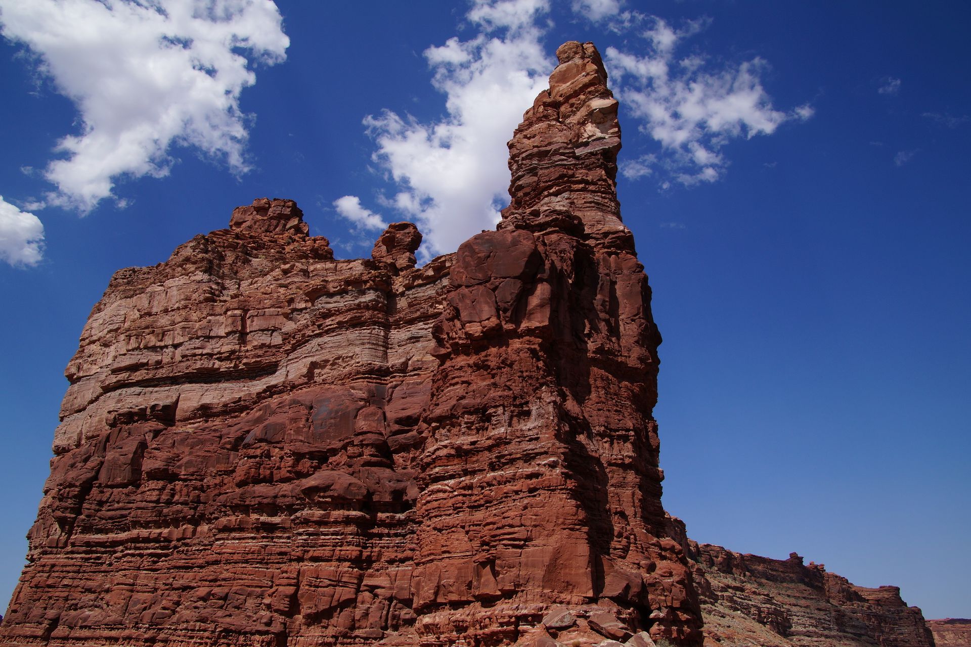 Red rock formation against a blue sky with white clouds.