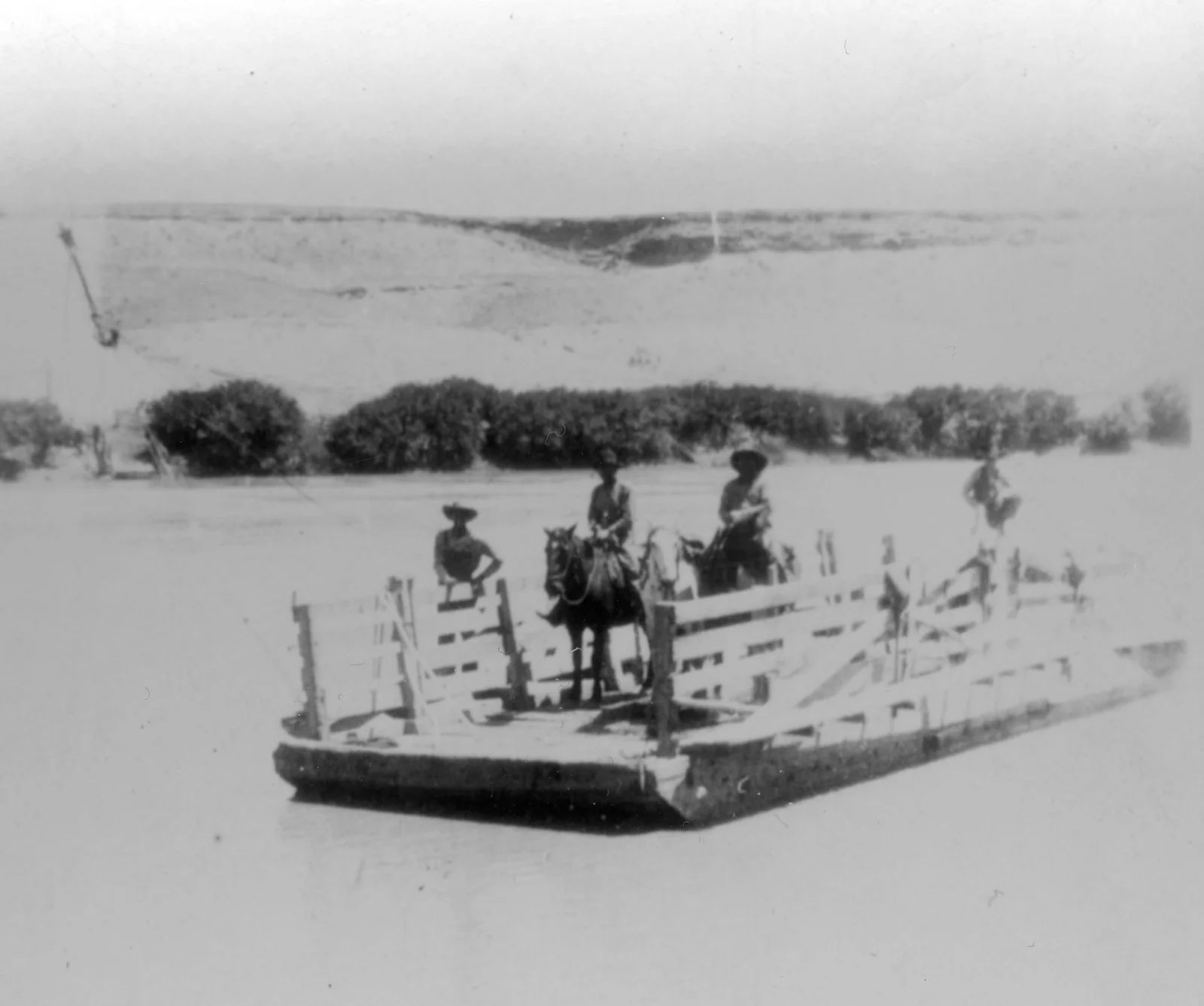 Ferry with three people and a horse crossing a river. Wooden structure, rural setting.