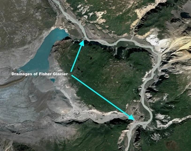 Aerial view of Fisher Glacier drainages, turquoise lake, and river flowing through rocky terrain.